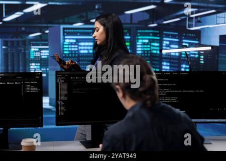 Technicians in data center workspace running system diagnostic tests and error checking utilities to fix problems. Employee looking for network issues affecting rigs performance and connectivity Stock Photo