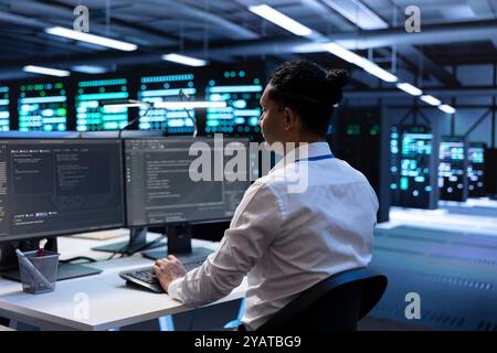 Admin in data center updating systems to keeps performance up and protect servers from easily exploitable software vulnerabilities. Worker looking for errors causing servers to slow down Stock Photo