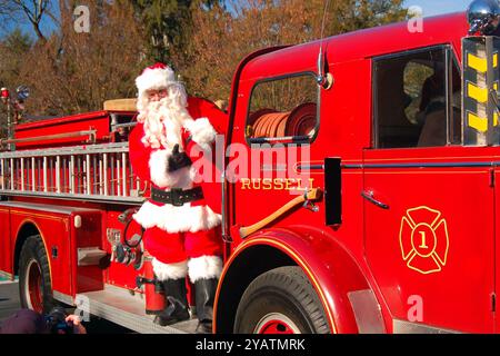 Santa Claus arrives in town chauffeured by the local firemen during a Christmas parade Stock Photo