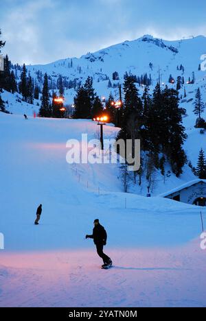 Snowboarders enjoy the last run of the day on the slopes in Squaw Valley, now called Olympic Valley, California Stock Photo