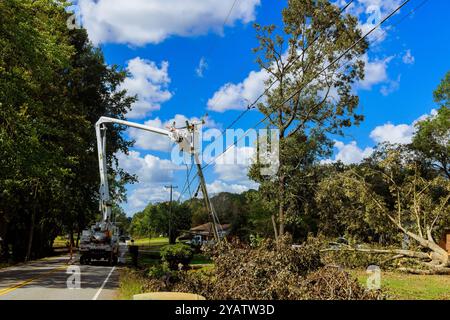 Emergency service linemen are diligently repairing power electrical lines damaged by hurricane using utility tower trucks Stock Photo