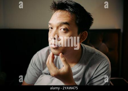A man examining his facial hair while touching his chin, appearing thoughtful and focused Stock Photo