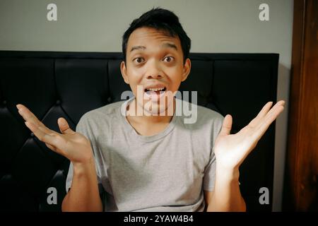 A young man expressing confusion or surprise with his hands raised in a questioning gesture Stock Photo