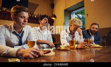 Group of colleagues share hearty laugh at bar, relaxed and enjoying their time together after work. Busy day and relax. Stock Photo