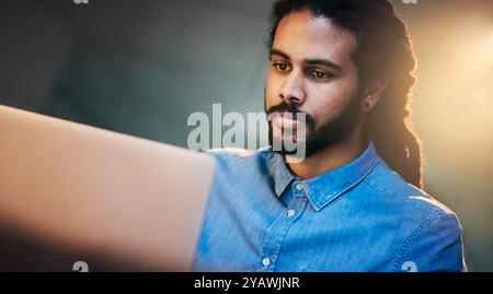 African man, laptop and night for deadline, communication or project management in office with app. Web designer, tech and research for target Stock Photo