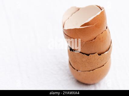Close-up of stacked broken brown eggshells on white background. Stock Photo