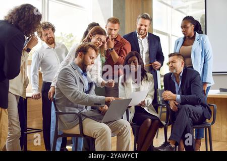 Team of diverse business men and women using laptop during work meeting in office Stock Photo