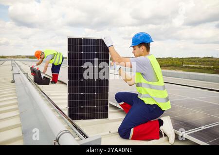 Electrician On Roof Installing Or Maintaining Solar Panels Stock Photo