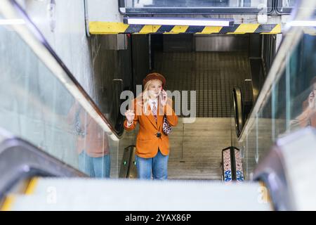 Young businesswoman talking on phone while leaving subway station Stock Photo