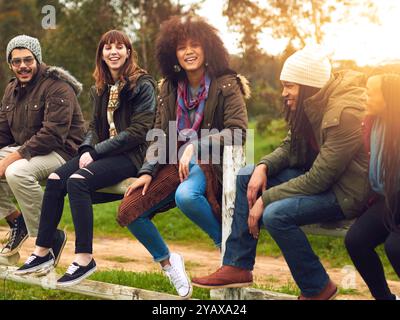 People, happy and outdoor on fence for travel, social gathering and relationship development. Friends, laugh and talking in nature for storytelling Stock Photo