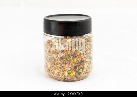 Mix Meva and Pan Masala with mixed dry fruits, fennel, seeds, and nuts scattered in a plastic transparent jar on white isolated background Stock Photo