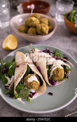 A wrap filled with homemade falafel, fresh vegetables, and sauce, ready to be enjoyed as a tasty meal Stock Photo