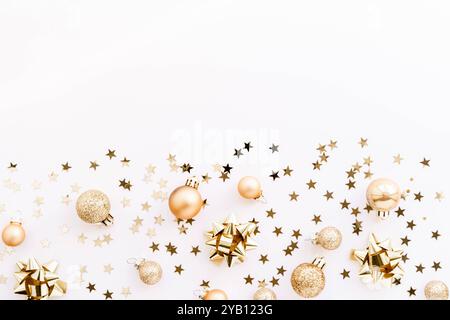 Festive flat-lay arrangement featuring golden Christmas ornaments, glittery baubles, and star-shaped confetti scattered across a light background. Top Stock Photo