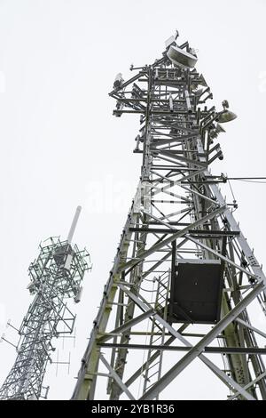 View from the ground upwards of two large mobile phone masts with many telecom dishes. Stock Photo