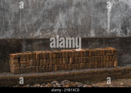 Stack of Old Red Bricks Against Rustic Wall | Construction Materials and Textures Stock Photo