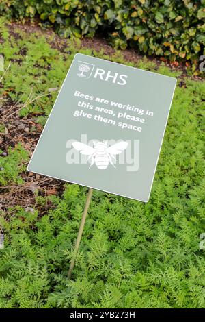 A sign saying 'Bees are working in this area, please give them space' at the RHS Garden Bridgewater Gardens, Worsley, Greater Manchester, England, UK Stock Photo