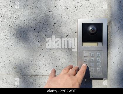 Hand pressing keypad on modern intercom device Stock Photo