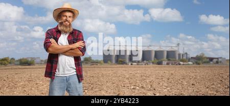 Farmer standing on a field with silos in the background Stock Photo