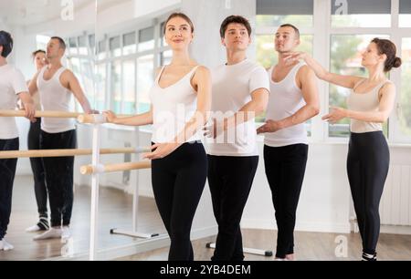Group practicing ballet positions at barre with female instructor Stock Photo