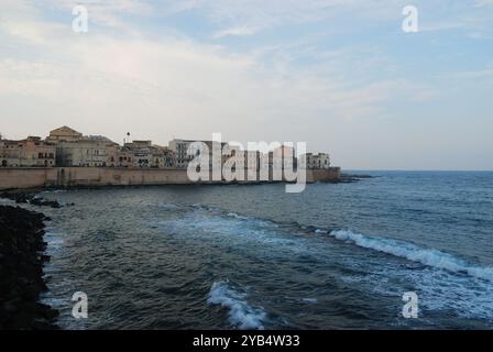 Ortigia shoreline at dusk, historic architecture meets the calm sea under a pastel sky Stock Photo