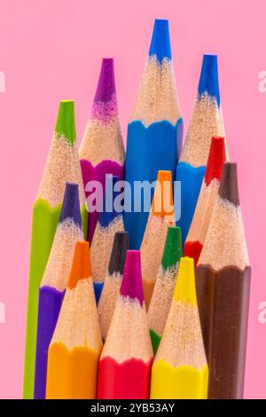 This image shows a close-up of several sharpened colored pencils with different colors pointing upwards against a pink background. Stock Photo
