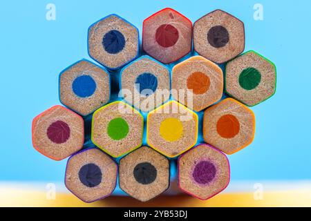 This image shows a close-up view of the back ends of a bundle of colored pencils arranged in a hexagonal pattern against a blue background. Stock Photo