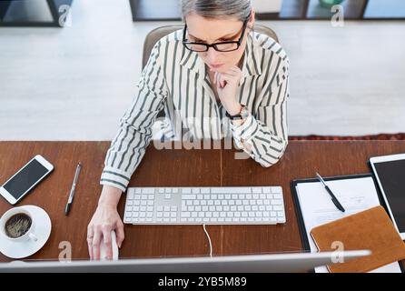 Thinking, reading and business woman on computer for problem solving, solution or email above. Planning, desktop and mature manager concentrating Stock Photo