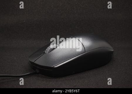Wired Mouse with two buttons and a center scroll button, black in color, placed against a black background Stock Photo
