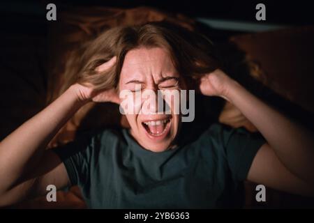 top view woman at night having anxiety and screaming while having nightmares, sleep disorder and panic attack. Stock Photo