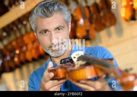 man with beard purchasing traditional violins in store Stock Photo