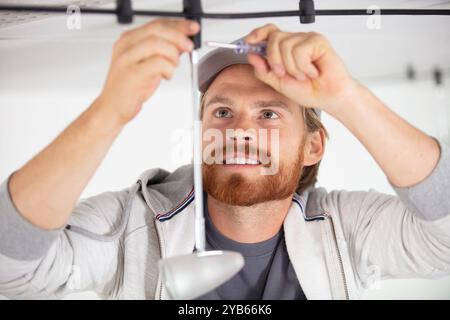 handsome young builder installing light Stock Photo