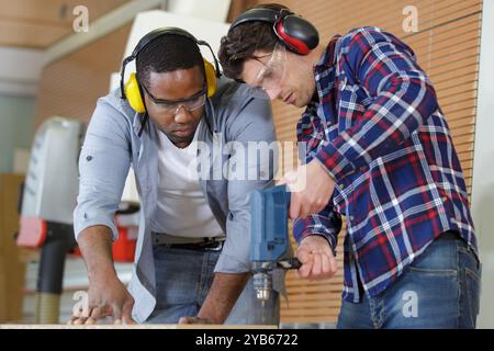 apprentice watching foreman use an electric drill Stock Photo