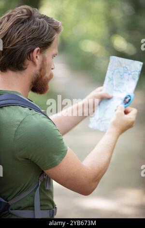 hiker in a forest using map and compass Stock Photo