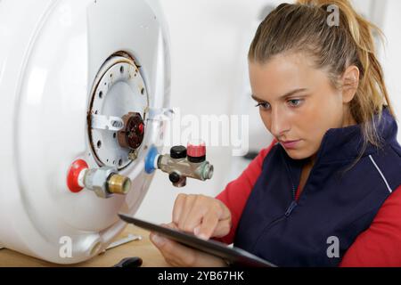 female plumber by boiler researching information on tablet Stock Photo