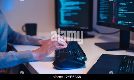 close up hand of Asian prompt engineer develop coding app with software data sitting in front of computer monitor at office Stock Photo