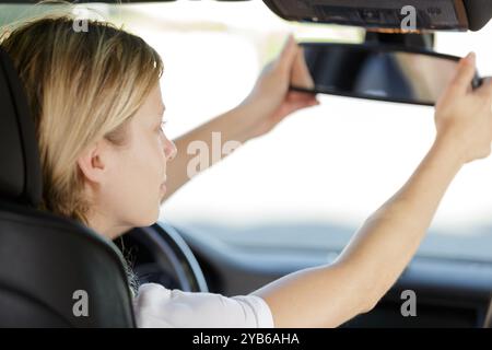 a woman is fixing the car rear mirror Stock Photo