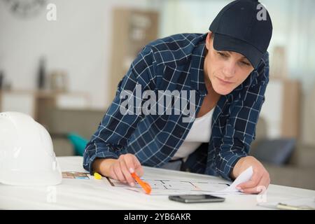 female architect studying plans on her desk Stock Photo