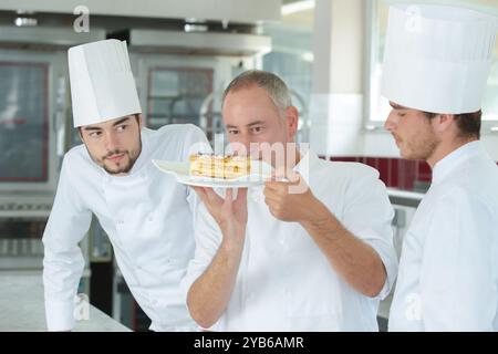 apprentices looking at chef during work in the kitchen Stock Photo