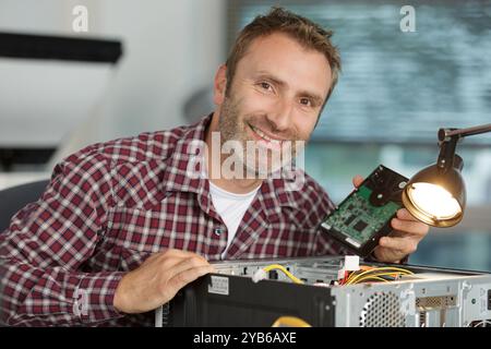 smiling man using multimeter while fixing pc Stock Photo