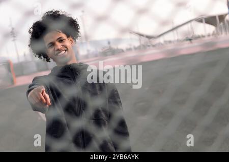 teen with curly hair behind metal chain link fence Stock Photo