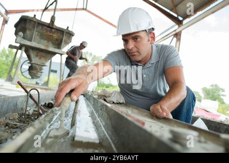 mature worker levelling cement with trowel Stock Photo