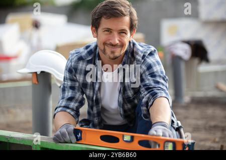 young handyman using spirit level outdoors Stock Photo