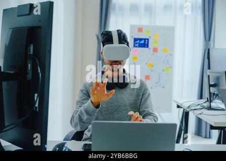 Asian and Indian developer program coding sent to virtual reality headset to implement ai project at office Stock Photo
