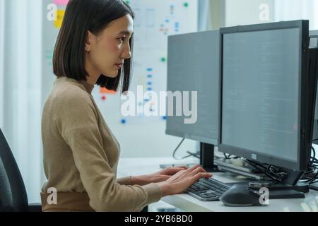 Asian prompt engineer develop coding app with software data sitting in front of computer monitor at office Stock Photo