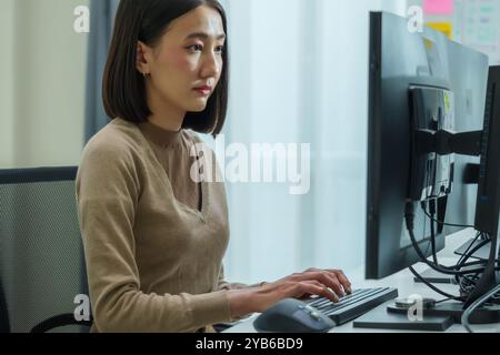 Asian prompt engineer develop coding app with software data sitting in front of computer monitor at office Stock Photo