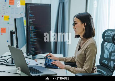 Asian prompt engineer develop coding app with software data sitting in front of computer monitor at office Stock Photo