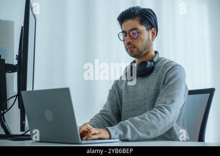 Asian man  prompt engineer develop coding app with software data sitting in front of computer monitor at office Stock Photo