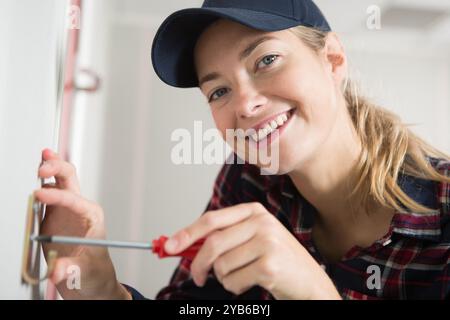 happy female technician is screwing an electric socket Stock Photo