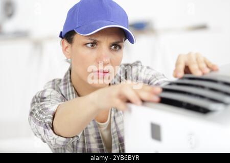 female technician cleaning air conditioner indoors Stock Photo