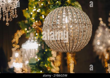 Round crystal chandelier hanging from the ceiling decorated with garland and string lights for the holidays Stock Photo